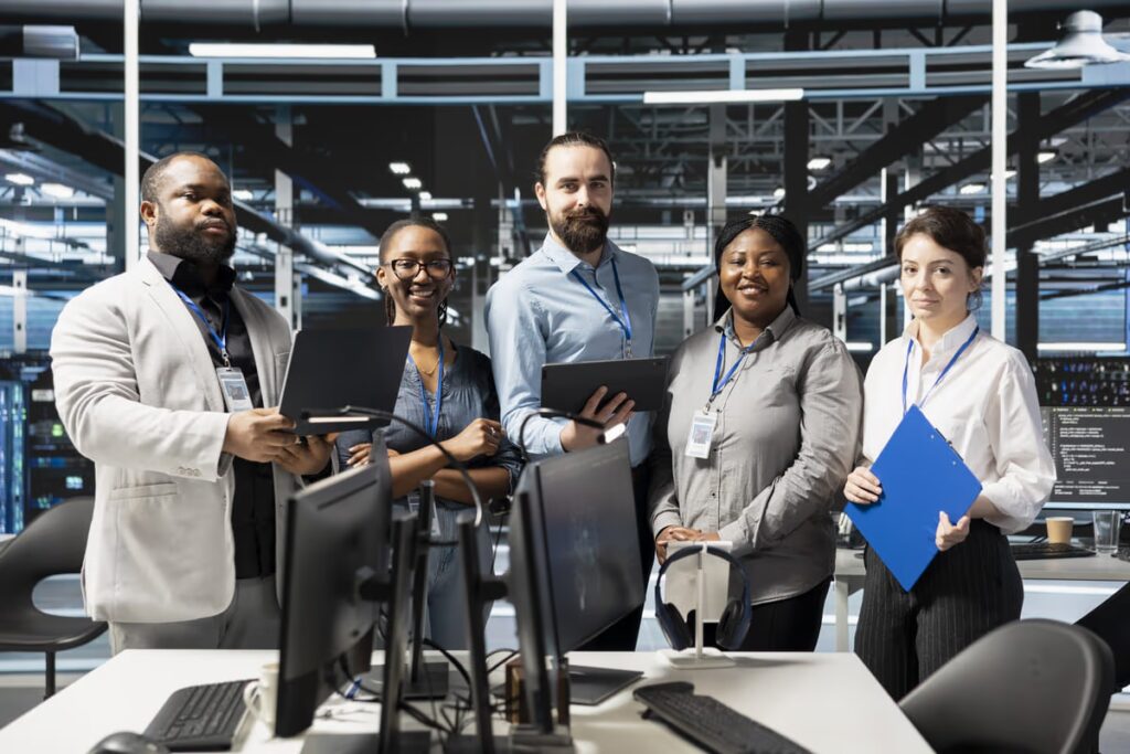 Diverse team of IT professionals standing in a modern data center, representing collaboration, technical expertise, and IT outsourcing services for business operations.