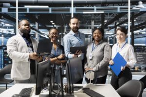 Diverse team of IT professionals standing in a modern data center, representing collaboration, technical expertise, and IT outsourcing services for business operations.