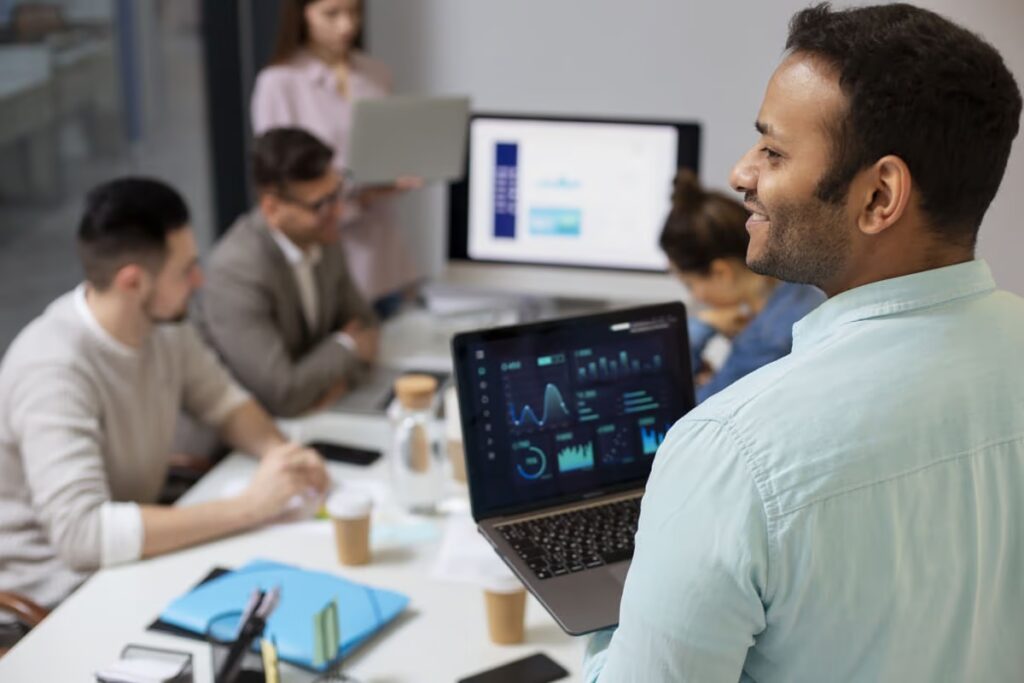 A developer presents performance data on a laptop during a team meeting, illustrating the successful outcomes of understanding what is CI/CD for automating software delivery and improving team collaboration.