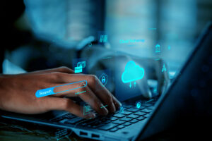 A user interacts with a laptop displaying a digital overlay of cloud and security icons, representing the implementation of CloudSecOps to secure cloud technology and data.