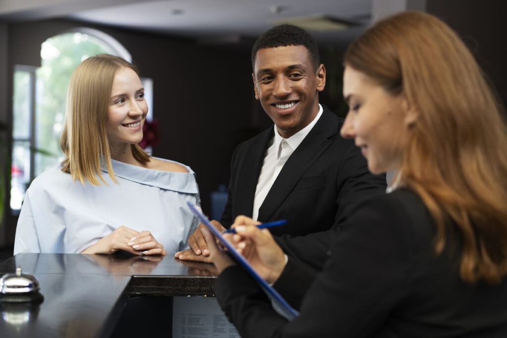 Smiling couple checks in at hotel reception desk, ensuring a premium guest experience.